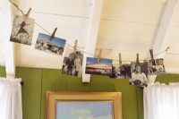 De vieilles photographies et cartes postales accrochées avec désinvolture avec des pinces à linge d'une ligne incarnent le style de vie de la maison de plage.