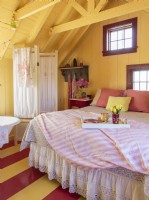 Les murs et le plafond jaunes enveloppent le lit et la salle de bain de soleil.
