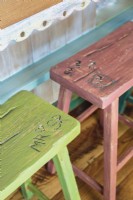 Les tabourets en bois Rw arborent une variété de couleurs et sont gravés des initiales des enfants.
