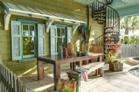 Un auvent en bois et des volets décoratifs donnent à la terrasse de la piscine une saveur caribéenne.