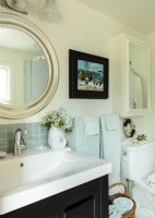 Des carreaux de dosseret en verre, une nouvelle vanité, un miroir rond - qui rappelle un hublot, rendent la salle de bain thermale jolie et confortable.