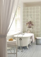 Un mur de blocs de verre entre la baignoire vintage et la douche offre une intimité.