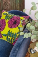 Un oreiller vintage à motif rose Marimenko ajoute un contraste audacieux à la chaise bleu foncé.