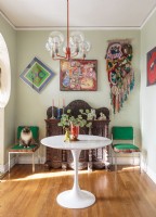 Les chaises vintage à structure métallique ont été recouvertes de velours vert et de tissu ikat. Un ruban de tulipe moderne du milieu du siècle se trouve sous un lustre italien.