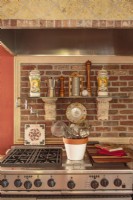 Ajoutant à la rusticité de la cuisine, une hotte recouverte de carreaux et de briques surmonte le poêle de qualité professionnelle et ajoute un caractère remarquable.