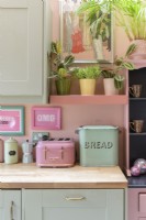 Détail du comptoir en bois de cuisine rétro avec une corbeille à pain vintage vert pâle et un grille-pain rose de style rétro