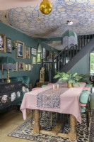 Coin repas ouvert vert foncé avec plafond tapissé de mosaïque et lampes de style art déco à franges