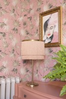 Lampe de table de style art déco à franges sur une commode récupérée devant du papier peint à motifs de feuilles de palmier