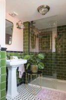 Blanc et lavabo et cabine de douche dans une salle de bains carrelée verte et rose pâle