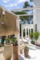 Pergola intégrée blanche et vue sur la piscine dans un jardin de style méditerranéen