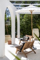 Chaises en bois et parasol sur terrasse blanche en été