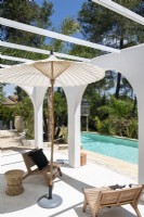Chaises simples et parasol à côté de la piscine en été