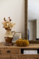 Arrangement de fleurs séchées dans un pichet en céramique et ornement de citrouille en velours