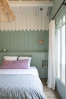 Murs en bois peints en bleu pastel et blanc dans une chambre de campagne