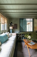 Coin salon cosy avec canapé intégré sous fenêtre et table vintage