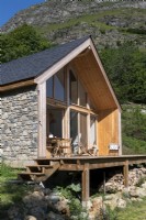Petite cabane en pierre et bois à côté de la montagne
