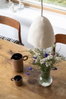 Arrangement de fleurs sauvages dans un vase sur une table à manger en bois