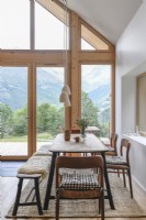 Salle à manger champêtre moderne avec vue sur la montagne à travers de grandes portes