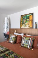 Planche de surf et œuvres d'art dans une chambre moderne avec literie à motifs