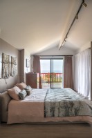 Chambre moderne avec portes coulissantes donnant sur balcon et vue côtière