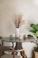 Vase en céramique de fleurs séchées sur une petite table en bois