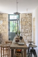 Table rustique dans une cuisine-salle à manger de campagne avec murs en pierres apparentes