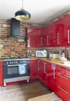 Mur de briques apparentes et armoires rouges dans une cuisine moderne