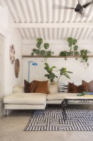Canapé en forme de L, tapis à motifs et plantes sur étagère dans le salon