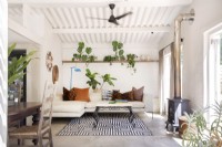 Salon avec canapé en L, tapis à motifs, plantes et cheminée