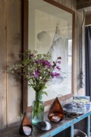 Vase de fleurs sauvages sur étagère avec peinture à voile moderne derrière
