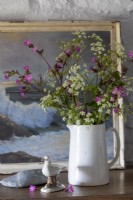Vase de fleurs sauvages sur une commode, vieille peinture maritime derrière et murs blanchis à la chaux