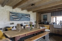 Cuisine rustique grande et confortable avec table de ferme en bois et grandes œuvres d'art modernes représentant des poissons dans une mer bleue.