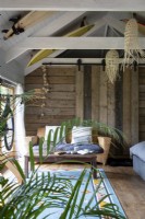 Grange convertie avec poutres apparentes, murs en bois rustiques et planches de surf comme décoration