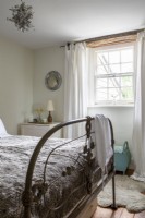 Chambre avec lit antique en fer et rideaux doux autour de la fenêtre