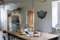 Maison de Sally et John Biddle à Cornwall, cuisine de campagne, avec murs et poutres blanchis à la chaux. Grande table de cuisine et cuisinière Aga.