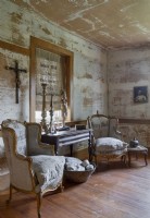 Fauteuils vintage dans un salon rustique avec peinture en détresse sur les murs