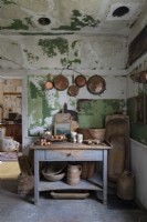 Casseroles et poêles en cuivre dans une cuisine rustique avec des meubles et des murs en détresse
