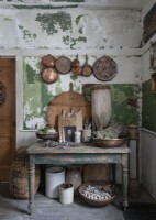Casseroles et poêles en cuivre sur un mur peint en détresse de cuisine rustique