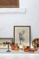 Détail de céramiques et peintures encadrées sur étagère murale blanche