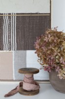 Chutes de tissu en lin sur bobine en bois à côté d'une composition florale