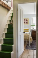 Vue sur une chambre de style vintage depuis le palier avec des escaliers peints en vert