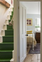 Escaliers peints en vert et vue sur la chambre depuis le palier