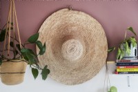 Détail d'un grand chapeau de paille sur un mur avec des plantes d'intérieur sur une étagère