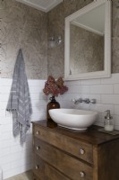 Lavabo sur commode en bois dans une salle de bains simple pays