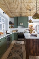 Cuisine de campagne avec armoires vertes et plafond en bois