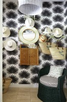 Une salle de chapeaux tropicaux avec du papier peint palmier nain noir et blanc et un mobilier vintage en osier. 