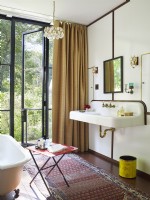 Salle de bain avec porte vers l'extérieur, baignoire sur pattes et lavabo vintage 