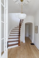 Escalier courbe blanc et bois dans un couloir de campagne minimal 