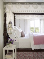 Chambre avec lit à baldaquin et draps blancs 