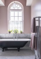 Salle de bain rose pastel avec baignoire sur pieds et porte-serviettes chromé 
